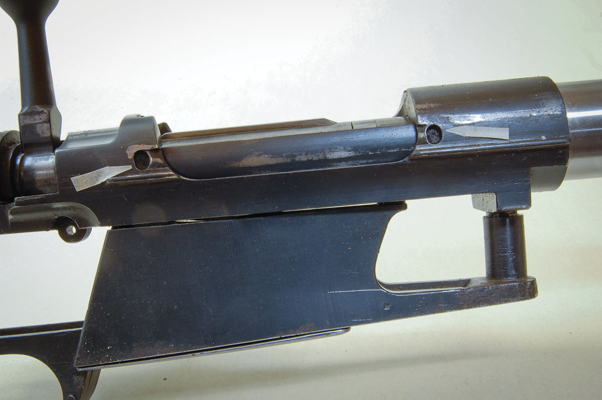 A sliding breech cover partially opened shows a hooked latch and the rails it slides on (see  arrows). The cover and rails must go.
